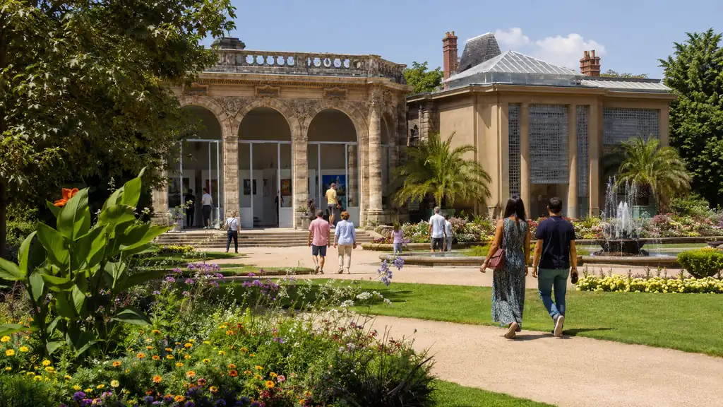 Orangerie du Thabor à Rennes avec visiteurs, jardins fleuris et espace d’exposition culturel.