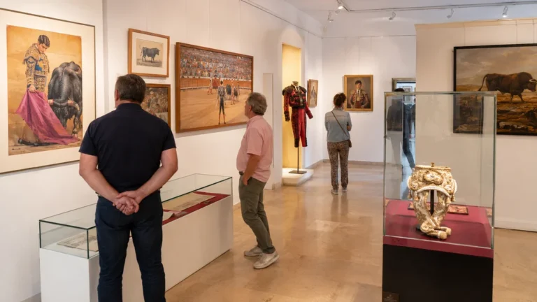 Musée des Cultures Taurines à Nîmes avec visiteurs observant costumes, affiches et œuvres taurines.