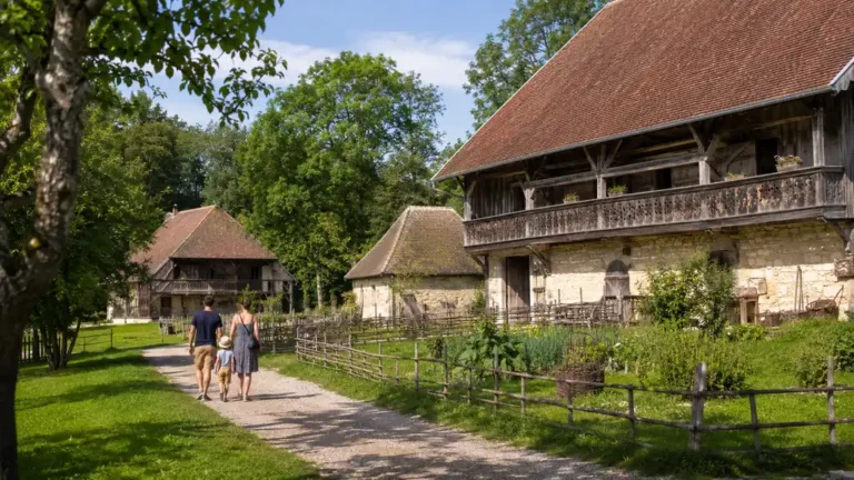 Famille visitant le Musée des Maisons comtoises de Nancray au milieu de maisons rurales traditionnelles en Franche-Comté